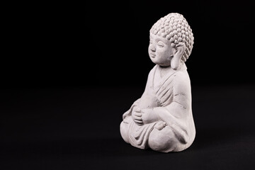 Minimalist close-up of a small Buddha statue on a black background. Ideal for concepts related to mindfulness, inner peace, spirituality, or meditation. 
