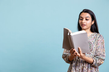 Positive jolly woman reading interesting book and enjoying lecture hobby, being entertained against...