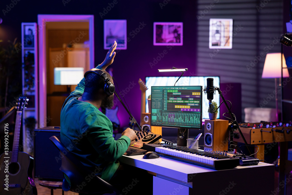 Poster confident music composer mixing sounds on digital audio software, creating a cool atmosphere in his 