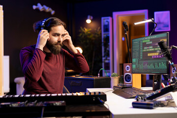 Audio engineer prepares recording tunes on daw software interface, working in music industry post production. Musician mixing and mastering songs, using headphones and soundboard.