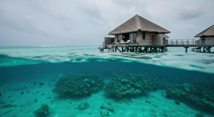 Fototapeta premium A stunning overwater bungalow stands proudly above the vibrant coral reef, surrounded by clear turquoise waters. The sky is overcast, adding a tranquil ambiance to this idyllic tropical destination