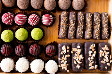 Assorted chocolate truffles and bars on a wooden tray with variety of toppings