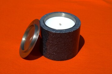 white candle in black jar with orange background