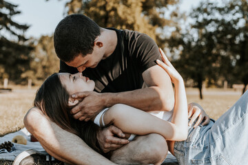 A young couple treats each other to apples for a picnic in the park.