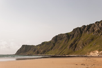 A beach with a rocky cliff in the background