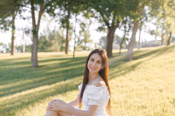 A young beautiful woman is sitting outdoor on a sunny morning. Relax in nature, happiness. Enjoying Summer days outdoors