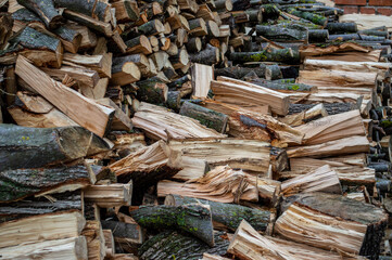 Piled firewood in a yard, showcasing various sizes of logs, perfect for heating and outdoor fires during the chilly months