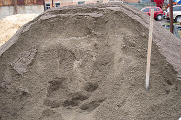 Workers prepare to use a large pile of sand at a construction site, showcasing urban development on...