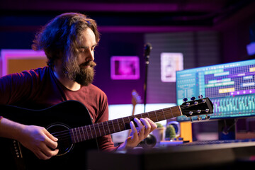 Skilled musician playing acoustic guitar and recording new tunes to use for mix and master...