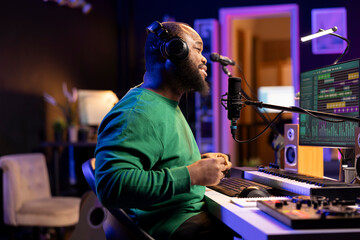 Young producer performing a live acoustic song in home studio, recording a new track on microphone...