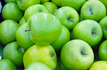 Fresh green apples stacked together, showcasing their bright color and natural texture, ideal for promoting healthy eating, fruit markets, or organic produce.