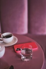 cup of tea and teapot and glass of water with phone at caffe table 