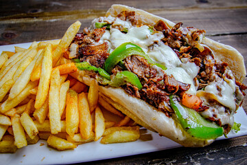 meat lover steak and cheese sandwich, served with a side of French fries and topped with melted cheese and grille peppers.