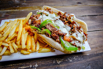 meat lover steak and cheese sandwich, served with a side of French fries and topped with melted cheese and grille peppers.