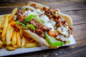 meat lover steak and cheese sandwich, served with a side of French fries and topped with melted cheese and grille peppers.