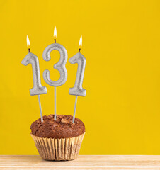 Chocolate cupcake with number 131 candle - Birthday on a yellow background