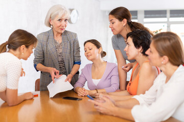 Female team leader holding meeting with group of fellow students, explaining details of new study project