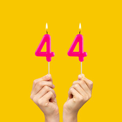 Birthday number 44 - Hands holding fuchsia colored candles