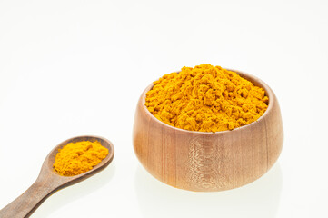 Finely dried turmeric powder in a bowl and wooden spoon - Curcuma longa