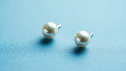 Overhead shot of matching pearl earrings on sky blue background, clean styling for jewelry showcase, no people