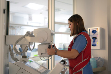 Female nurse preparing portable x-ray machine in hospital room