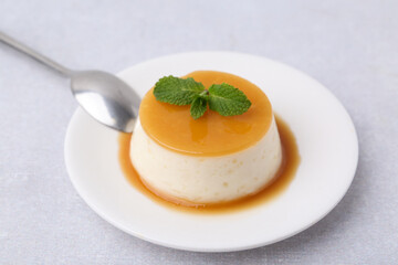 Tasty pudding with caramel sauce served on white table, closeup