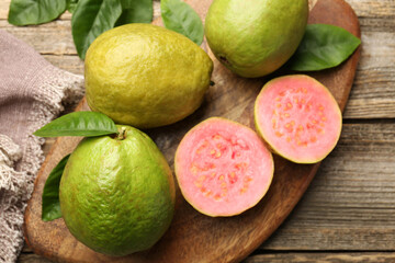 Fresh whole and cut guava fruits on wooden table, above view