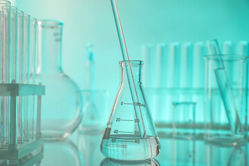Laboratory glassware on mirror surface against turquoise background