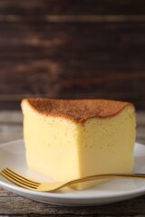 Piece of tasty Japanese Castella sponge cake and fork on table, closeup