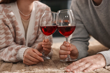 Couple with glasses of wine on floor at home, closeup