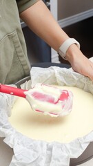 Deliciously Smooth Cake Batter Being Mixed with a Red Spatula in a Black Round Cake Pan