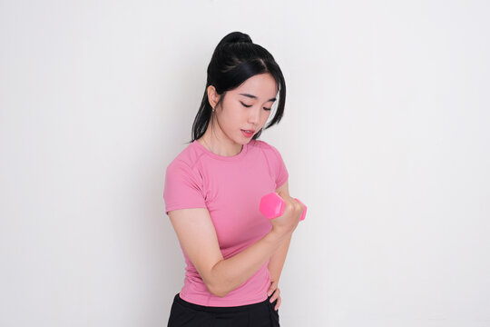 A young women showing focus expression while lifting a dumbbell