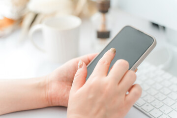 スマホ・スマートフォンの画面をタッチするネイルをした女性
