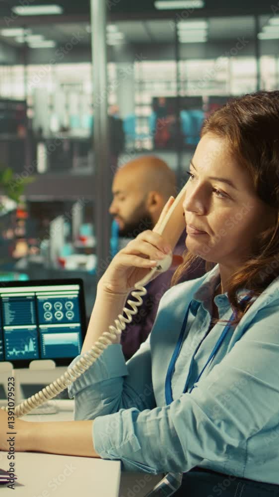 Poster vertical video worker in office using landline phone to talk with client while reviewing charts. emp
