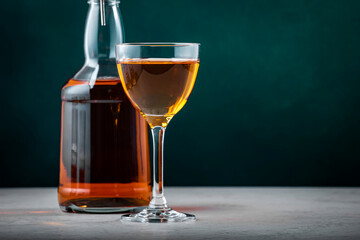 Spanish sherry brandy in glass with bottle on dark green background