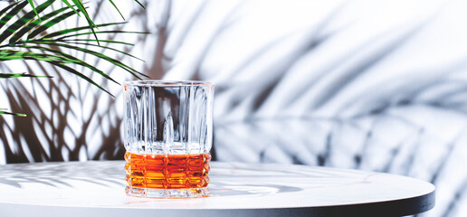 Japanese blended whiskey in glass. White  background with tropical leaves, hard light