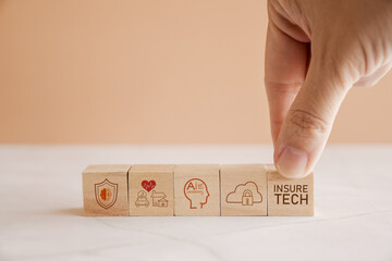 Hands holding wooden blocks with Insurtech and Insurance technology icons
