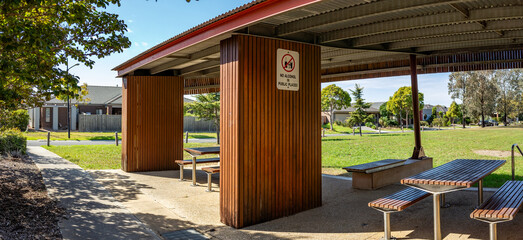 Outdoor park shelter or covered pavilion with picnic tables and benches for community gatherings in...