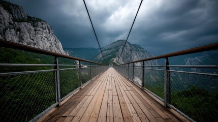 Obraz premium Suspension Bridge Between Mountains Under Cloudy Sky