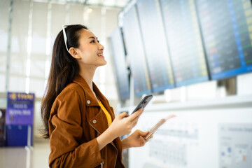 happy young asian woman traveler holding boarding pass ticket, passport and smartphone at the...