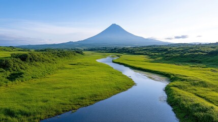 Fototapeta premium Serene landscape with a winding river, lush greenery, and a majestic volcano in the distance