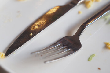 Dining utensils on a plate after a meal in a restaurant setting