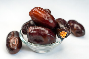 Macro shot of dried dates in a glass bowl on a white background. Sweet, nutritious, and rich in...