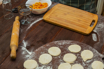 Circles of cookie dough on a table sprinkled with flour next to a rolling pin