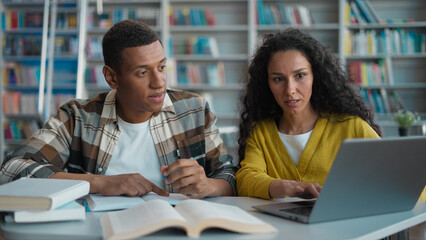 Classmates students African American man Arabian Latina woman together work high school library...