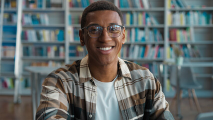 Obraz premium African American man guy male typing browsing laptop online computer high school library university student studying learning e-learning looking at camera smiling internet networking texting college