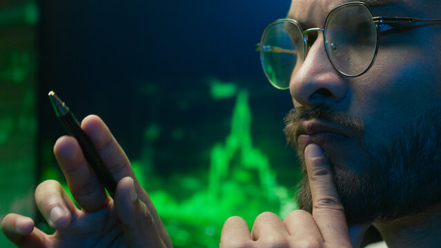 Arabian Indian man analyst programmer holding pen pointing coder hacker work planning male pondering thinking imagination businessman calculating contemplation strategy guy inspiration solve business