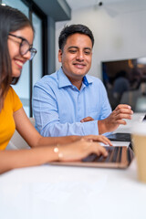 Latin businesspeople working together on laptop in coworking space