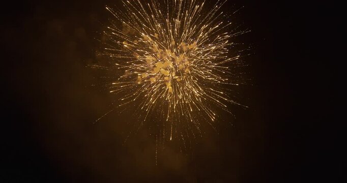 Rapid fireworks exploding one after the other in night sky with smoke lingering