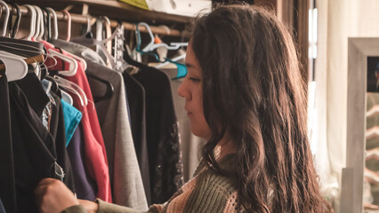 Young woman choosing outfit from her closet